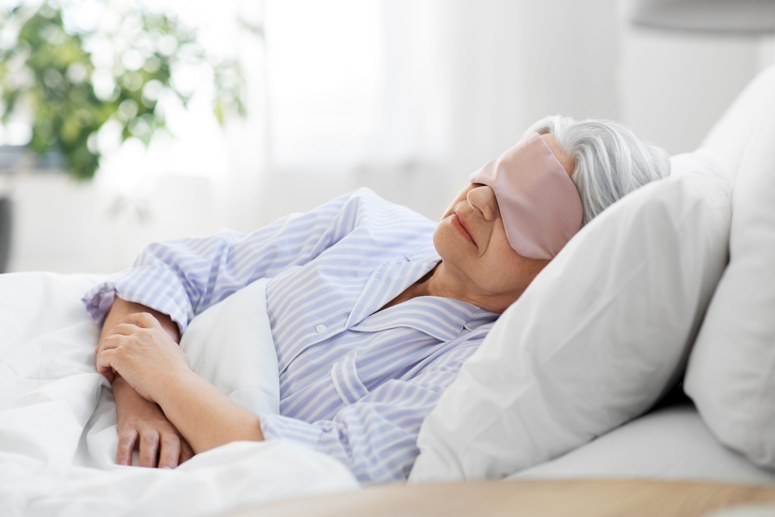 senior woman with eye mask sleeping in bed at home